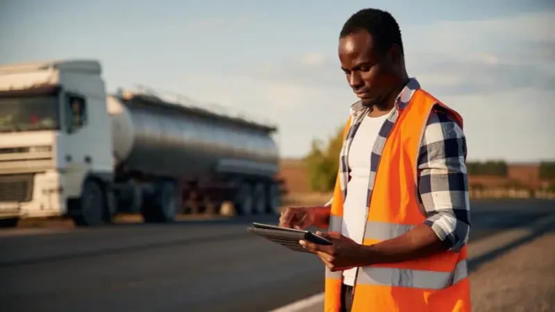 Man with tablet inspecting commercial truck on roadside